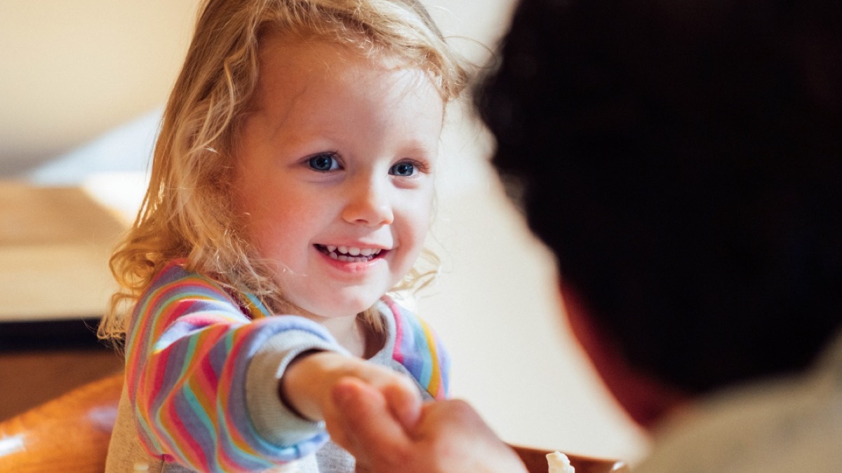A child smiling while connecting with a grown-up across a chessboard