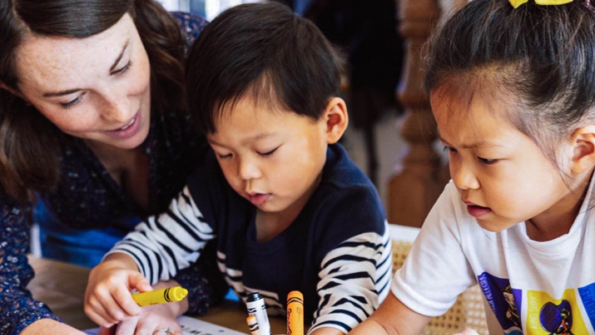 A teacher guiding two children through a classroom activity